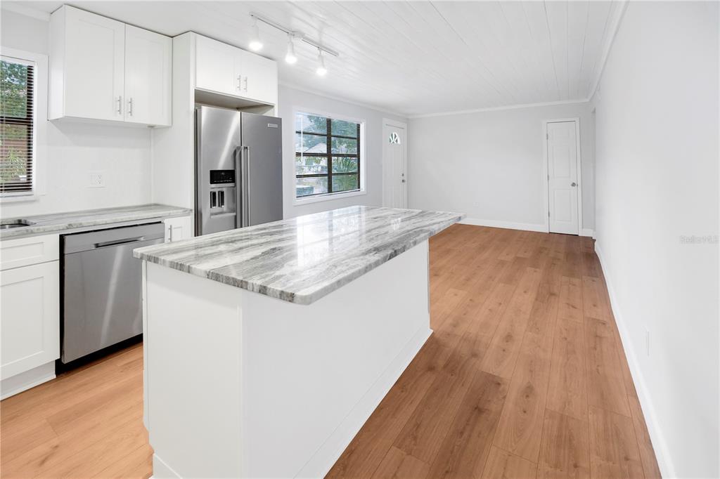 A modern kitchen features white cabinets, stainless steel appliances, and a marble-topped island — 6425 S RICHARD AVENUE, TAMPA, FL