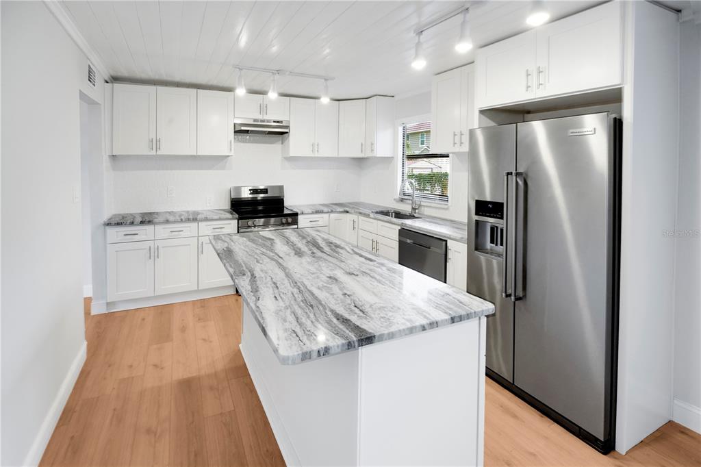 A kitchen features white cabinets, marble-patterned countertops, a center island, and stainless steel appliances — 6425 S RICHARD AVENUE, TAMPA, FL