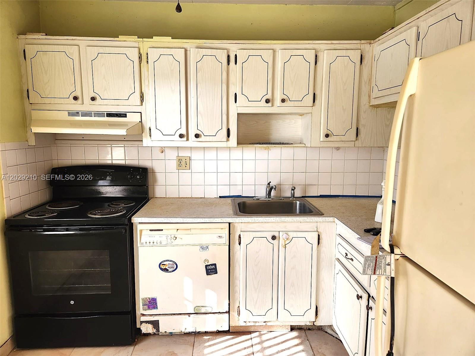 A kitchen features white wood-grain cabinets, a black electric stove, a dishwasher, and tiled walls — 7787 Golf Circle Drive # 109, Margate FL 33063, MARGATE, FL