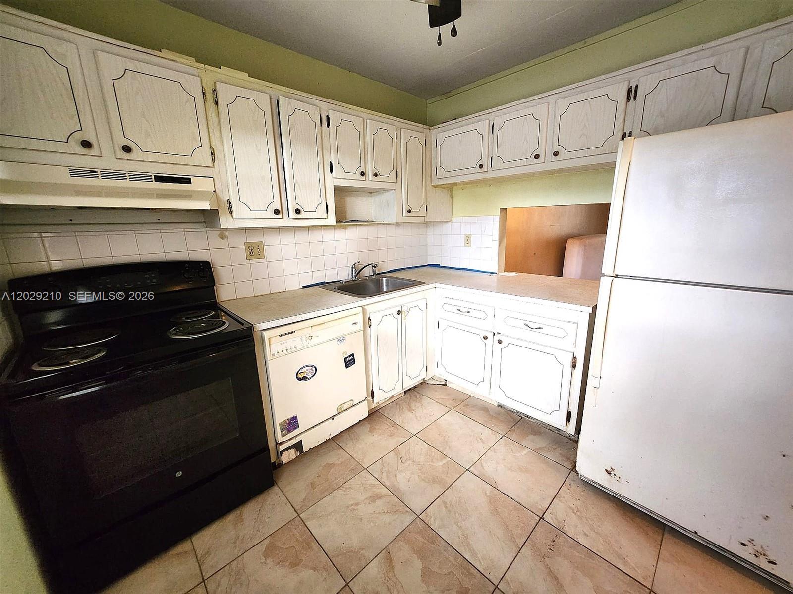 A kitchen features white cabinets, a black stove, a dishwasher, and light-colored tile flooring — 7787 Golf Circle Drive # 109, Margate FL 33063, MARGATE, FL