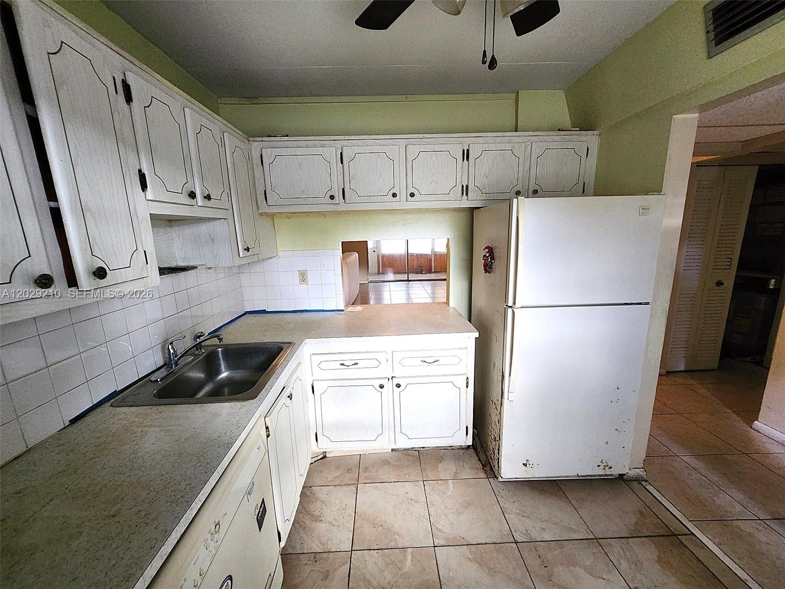 A kitchen features white cabinets, a stainless steel sink, and a white refrigerator — 7787 Golf Circle Drive # 109, Margate FL 33063, MARGATE, FL