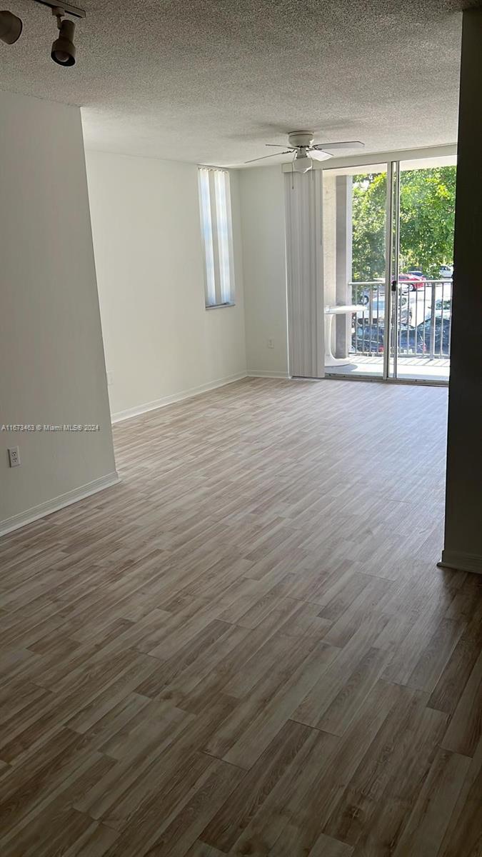 An empty living room features light wood-look flooring, a ceiling fan, and a sliding glass door — 4350 NW 107th Ave # 2, Doral FL 33178, DORAL, FL
