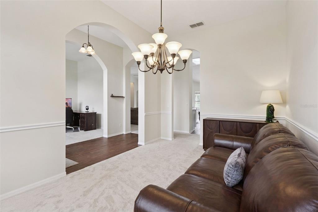 A living room with a leather sofa, chandelier, and arched doorways leading to other rooms — 14313 ROXSHIRE DRIVE, ORLANDO, FL