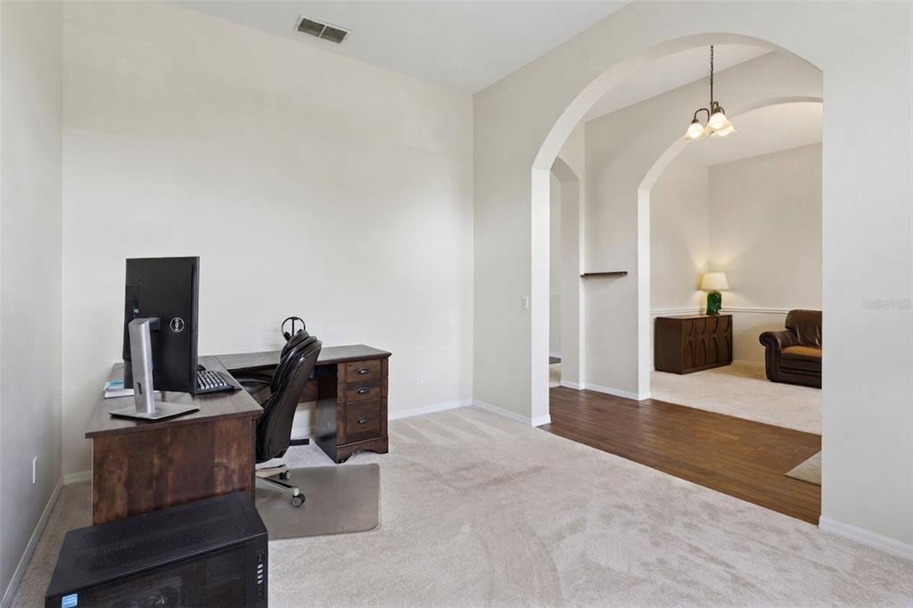 A home office with a desk and computer leads into an adjacent room through an archway — 14313 ROXSHIRE DRIVE, ORLANDO, FL