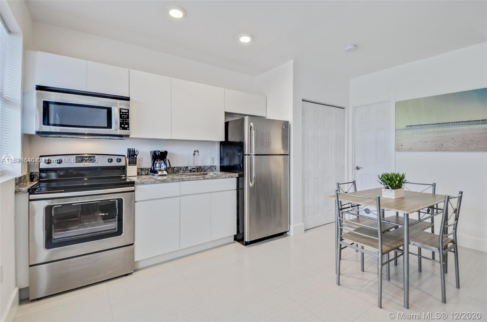 A kitchen features white cabinets, stainless steel appliances, granite countertops, and a small dining set — 2601 NW 1st Ave # 4, Miami FL 33127, MIAMI, FL