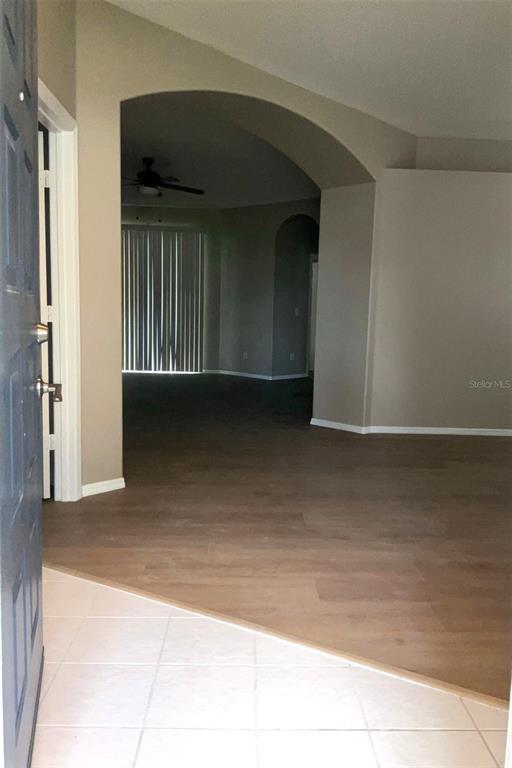 An entryway with tiled flooring transitions into a living area featuring wood-look floors and arches — 1318 LAKE BISCAYNE WAY, ORLANDO, FL