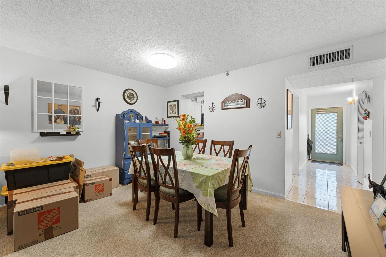A dining room features a table with six chairs, a blue hutch, and moving boxes — 14527 Bonaire Boulevard # 109, Delray Beach FL 33446, DELRAY BEACH, FL