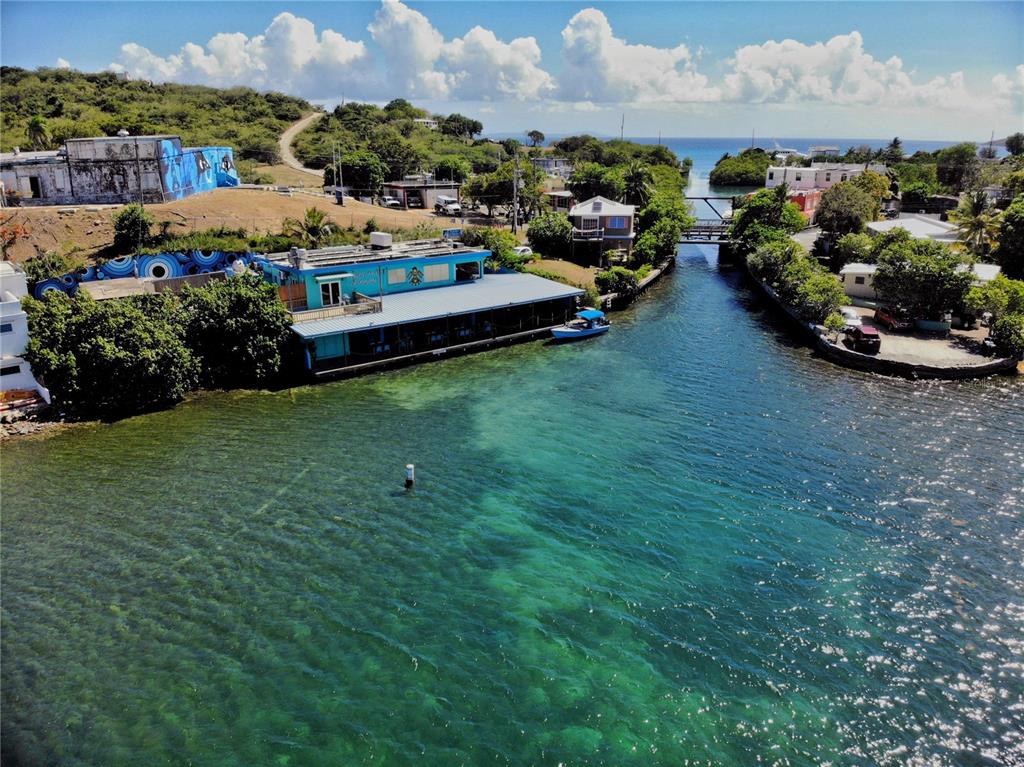 An aerial view shows a blue waterfront building beside a narrow channel with a bridge — 372 CALLE FULLADOZA, CULEBRA, PR