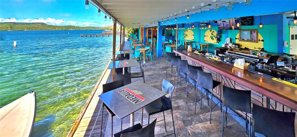 An outdoor waterfront bar features a long wooden counter, metal tables, and chairs — 372 CALLE FULLADOZA, CULEBRA, PR
