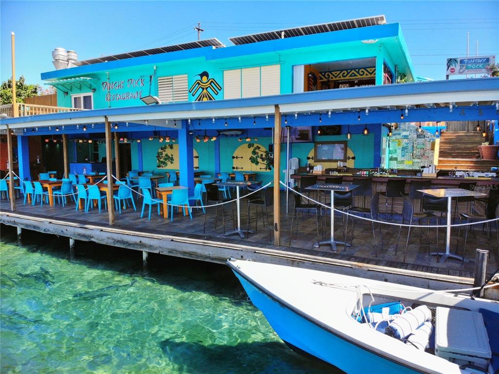 An outdoor waterfront restaurant deck features blue chairs, tables, and a boat docked alongside — 372 CALLE FULLADOZA, CULEBRA, PR