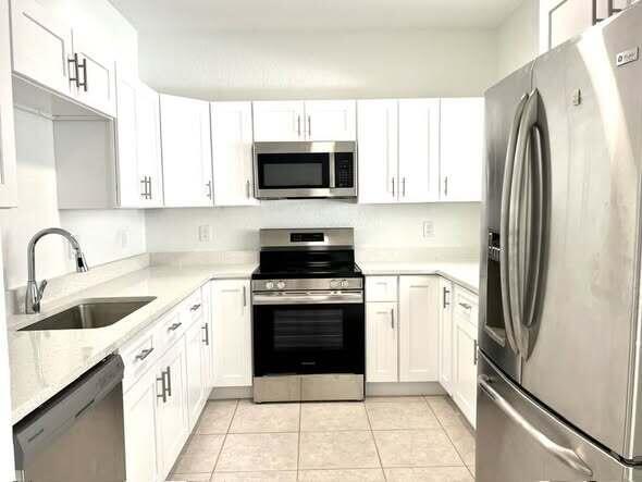 A kitchen features white cabinets, stainless steel appliances, and light-colored countertops — 1434 Hawthorne Place, Wellington FL 33414, WELLINGTON, FL