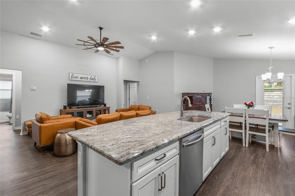 An open-concept kitchen with a granite island overlooks a living area and dining space — 2311 SUNSET WAY, DAVENPORT, FL