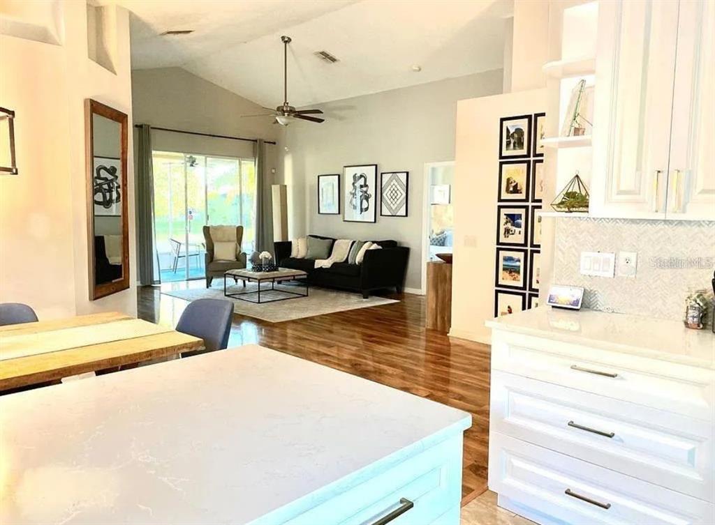 A kitchen island overlooks an open-concept living room with hardwood floors and a sliding door — 31352 GOLDEN GATE DRIVE, WESLEY CHAPEL, FL