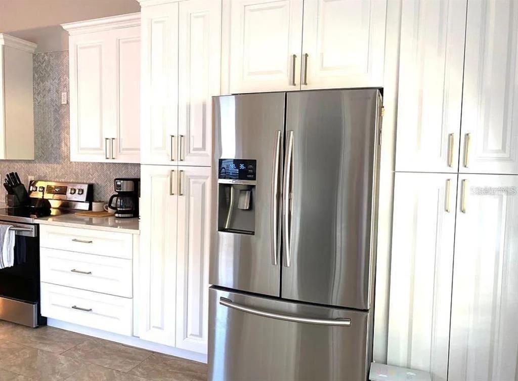 A kitchen features white cabinetry, stainless steel appliances, and a herringbone-patterned backsplash — 31352 GOLDEN GATE DRIVE, WESLEY CHAPEL, FL