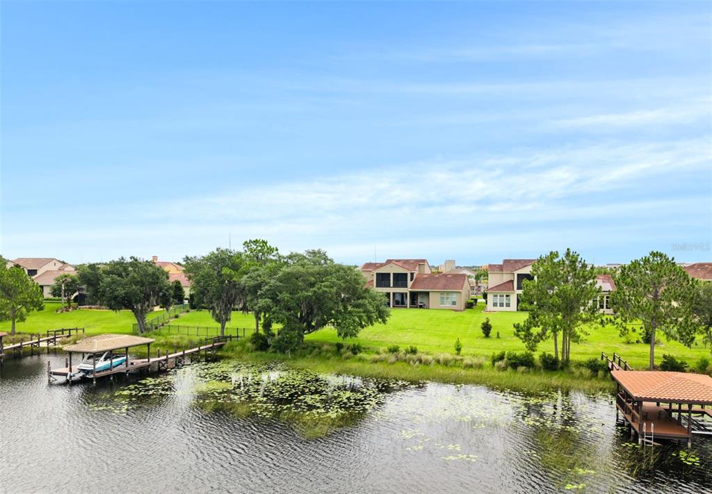 An aerial view shows a lake with two boat docks and houses on a grassy lawn — 8750 BAYVIEW CROSSING DRIVE, WINTER GARDEN, FL