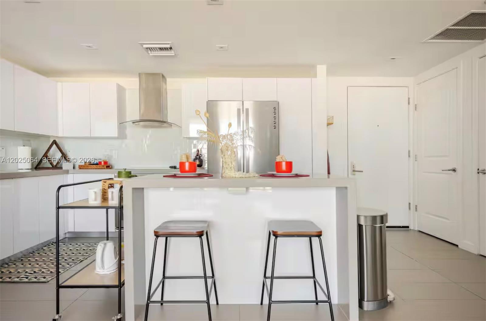 A modern kitchen features white cabinetry, stainless steel appliances, a central island, and two stools — 1600 NE 1 AVE # 3519, Miami FL 33132, MIAMI, FL