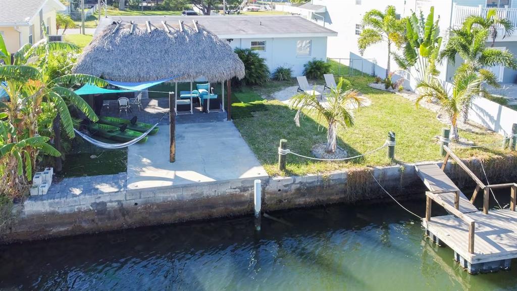 An aerial view of a backyard featuring a tiki hut, patio, lawn, and private dock — 13912 DULEY AVENUE, HUDSON, FL