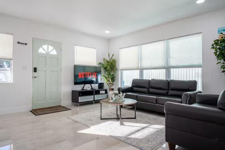 A living room features a light green front door, black leather furniture, and large windows — 13912 DULEY AVENUE, HUDSON, FL