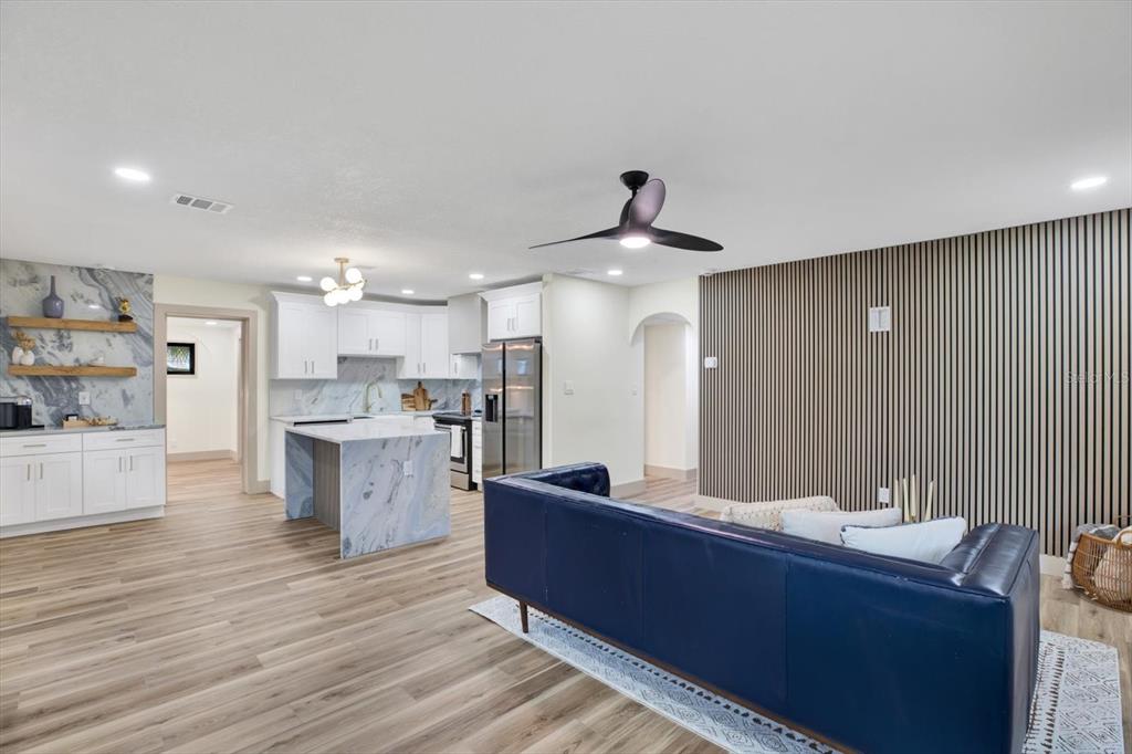 An open-concept kitchen and living area featuring a blue marble island and slatted wood wall — 203 DRIFTWOOD DRIVE W, PALM HARBOR, FL