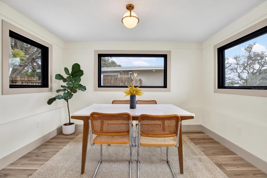 A dining room features a white table, four cane chairs, and three windows with black frames — 203 DRIFTWOOD DRIVE W, PALM HARBOR, FL