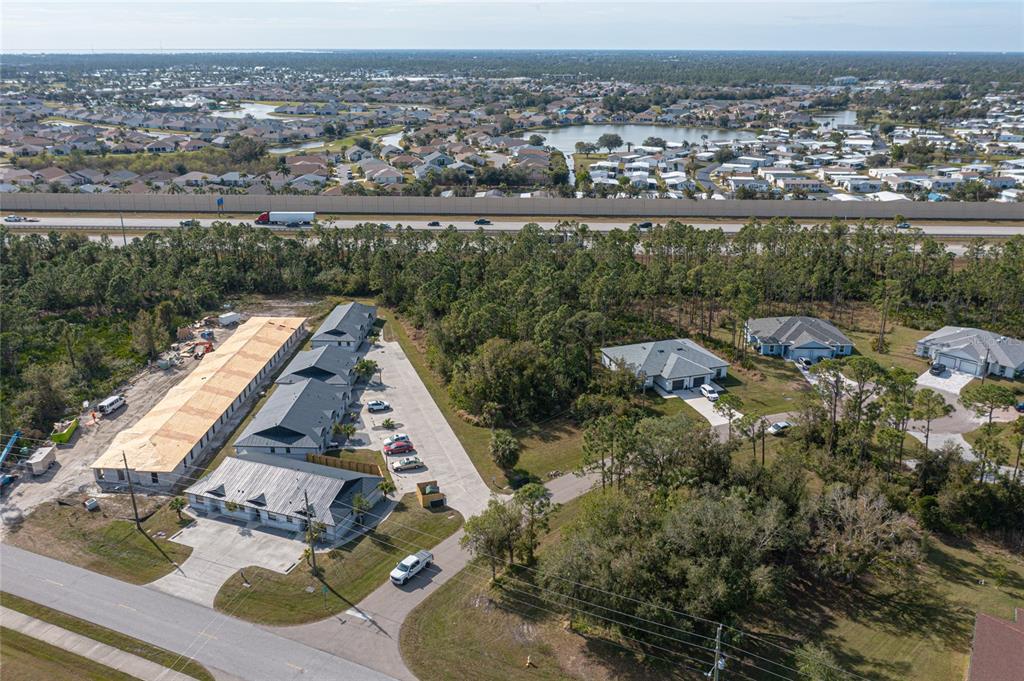 An aerial view shows a multi-unit residential building under construction next to existing suburban homes — 24511 ZEPHYR COURT, PUNTA GORDA, FL