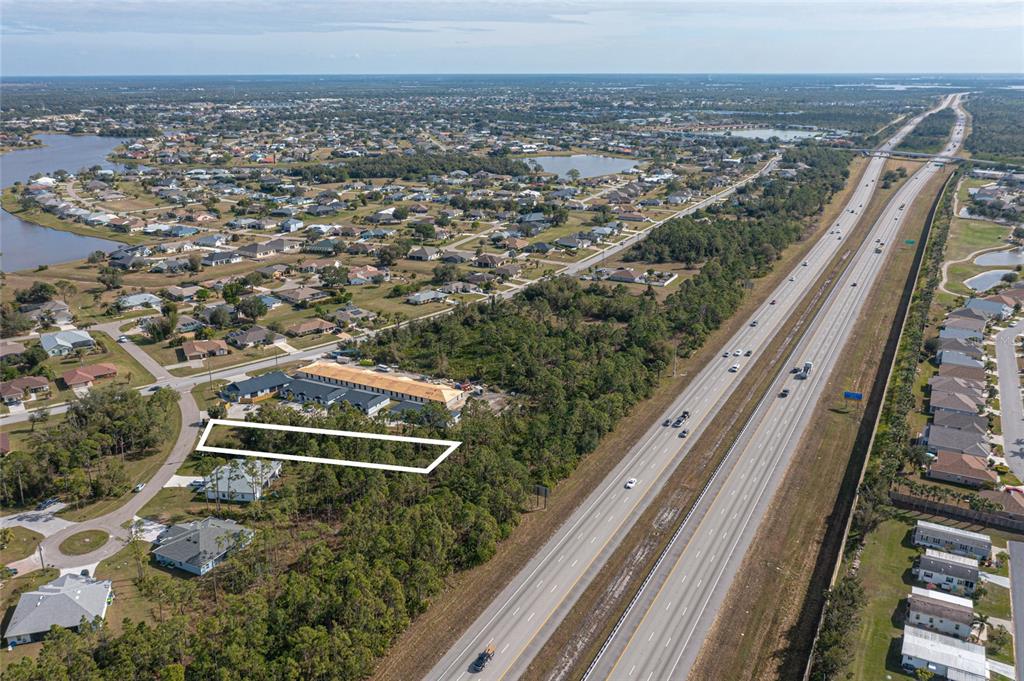 An aerial view shows a rectangular plot of land adjacent to a highway and residential area — 24511 ZEPHYR COURT, PUNTA GORDA, FL