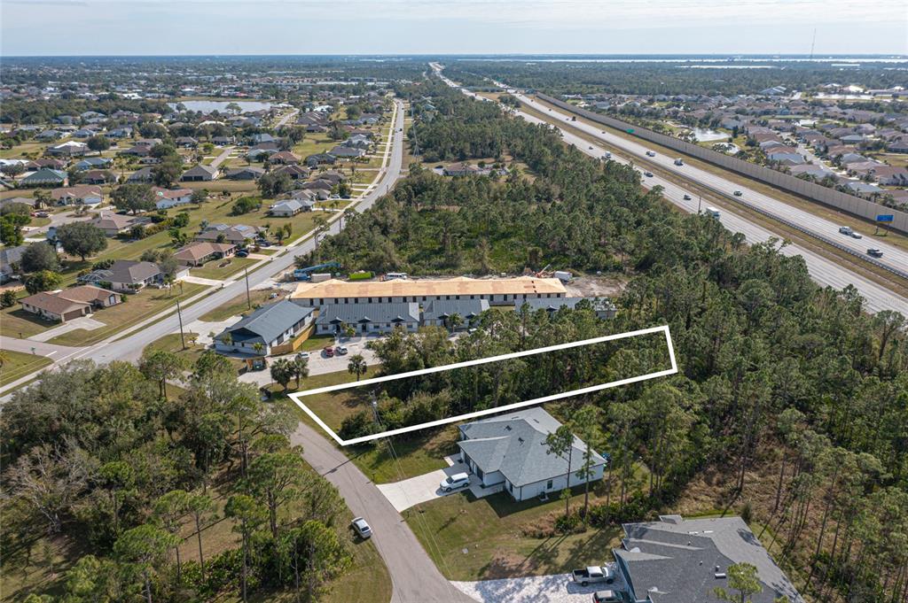 An aerial view shows a rectangular plot of land outlined in white near a highway — 24511 ZEPHYR COURT, PUNTA GORDA, FL