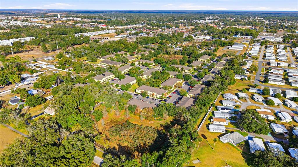 An aerial view shows a residential complex surrounded by trees and neighboring mobile home parks — 37548 DALIHA TERRACE, ZEPHYRHILLS, FL
