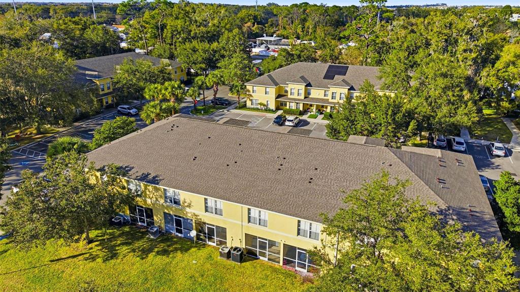 An aerial view of yellow multi-story apartment buildings surrounded by trees and parking lots — 37548 DALIHA TERRACE, ZEPHYRHILLS, FL