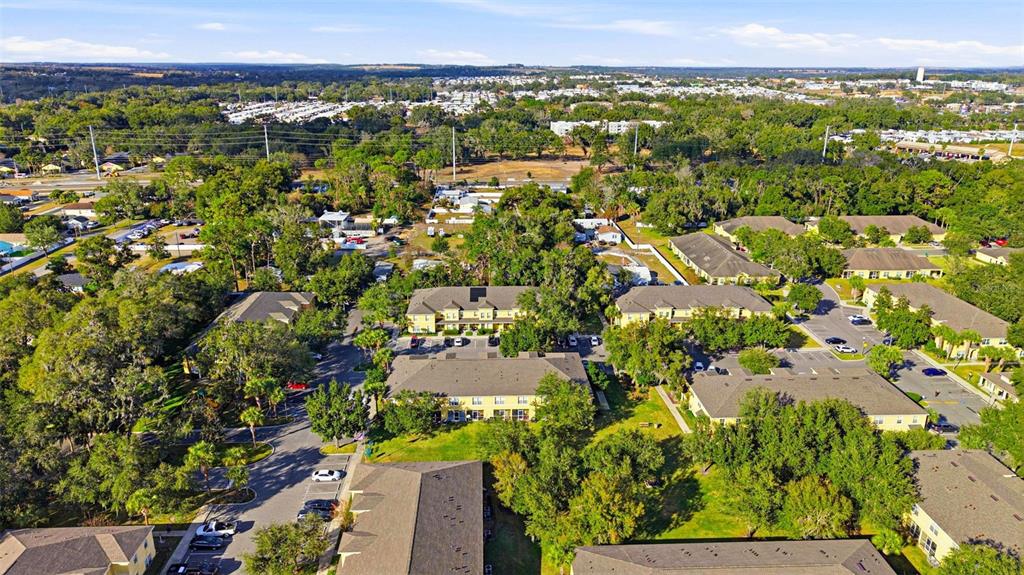 An aerial view shows several multi-story apartment buildings surrounded by trees and parking lots — 37548 DALIHA TERRACE, ZEPHYRHILLS, FL
