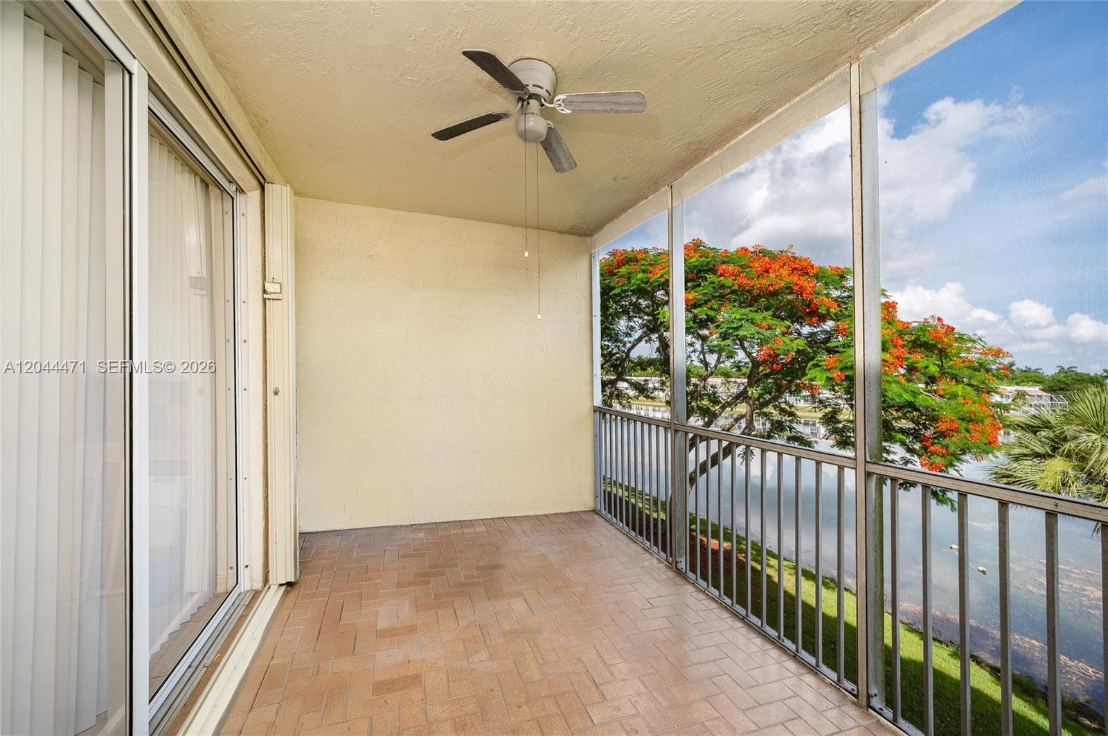 A screened-in balcony features a ceiling fan, tiled flooring, and a view of water — 10750 NW 66th St # 312, Doral FL 33178, DORAL, FL
