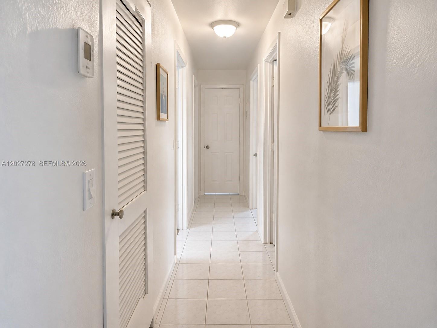 A hallway with white walls, tiled flooring, and several closed interior doors — 901 NE 2nd St, Hallandale Beach FL 33009, HALLANDALE BEACH, FL