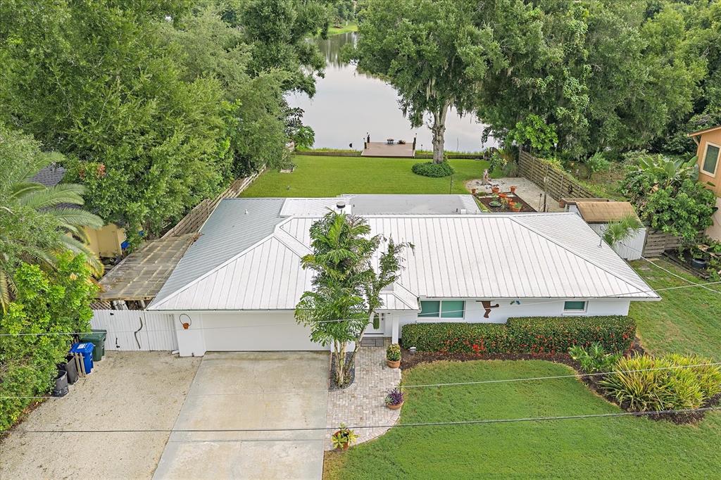 An aerial view of a single-story house with a metal roof, driveway, and backyard lake — 4271 LAGO WAY, SARASOTA, FL