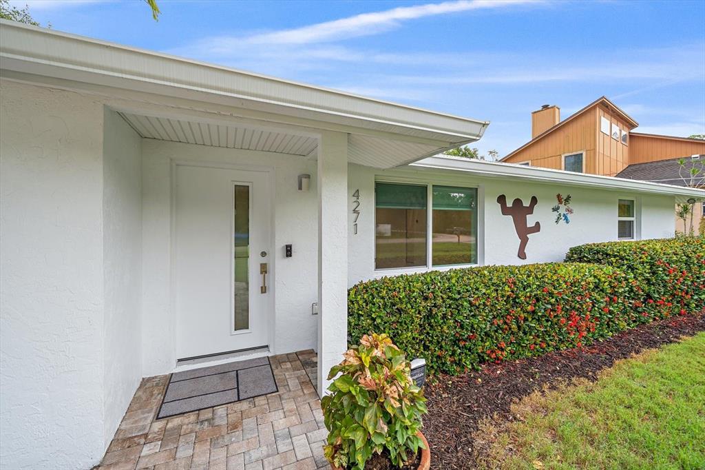 The exterior of a white house features a front door, a window, and a hedge — 4271 LAGO WAY, SARASOTA, FL