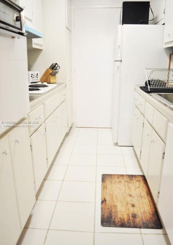 A narrow kitchen features white cabinets, white appliances, and light-colored floor tiles — 100 Lincoln Rd # 522, Miami Beach FL 33139, MIAMI BEACH, FL