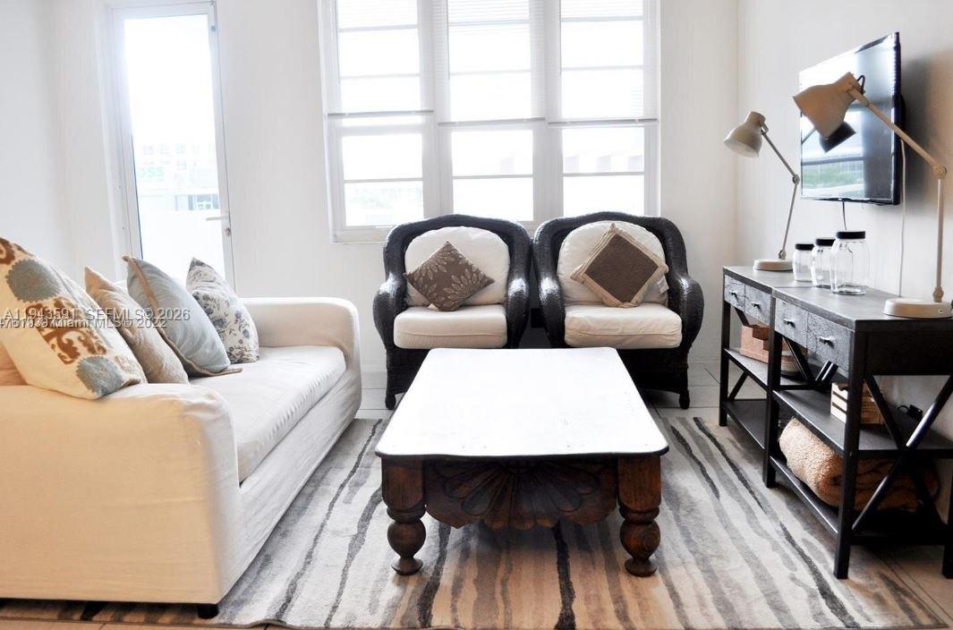 A living room features a white sofa, two wicker chairs, a coffee table, and a console — 100 Lincoln Rd # 522, Miami Beach FL 33139, MIAMI BEACH, FL