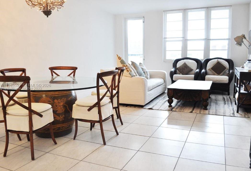 A dining area with a glass table and chairs sits adjacent to a living room — 100 Lincoln Rd # 522, Miami Beach FL 33139, MIAMI BEACH, FL