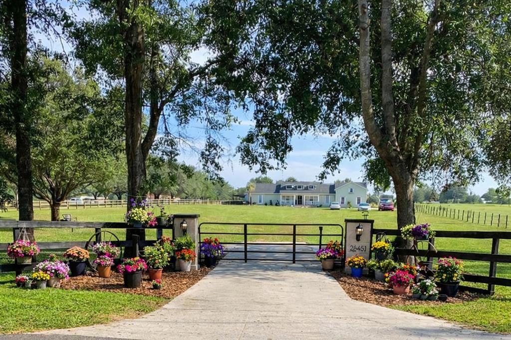 A gated driveway leads to a house set back on a large, grassy, tree-lined lot — 20851 SW 36TH STREET, DUNNELLON, FL