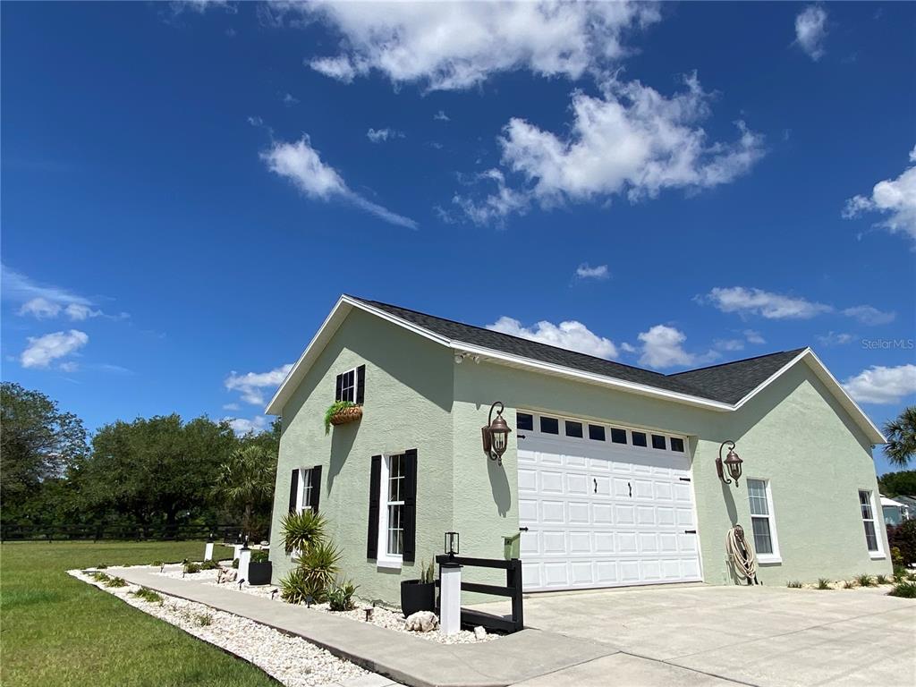 A light green detached garage with a white door and black shutters under a blue sky — 20851 SW 36TH STREET, DUNNELLON, FL