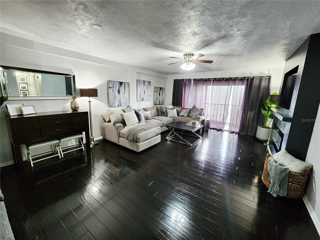 A living room features dark hardwood floors, a sectional sofa, and a fireplace — 4651 1ST STREET NE UNIT 306, ST PETERSBURG, FL