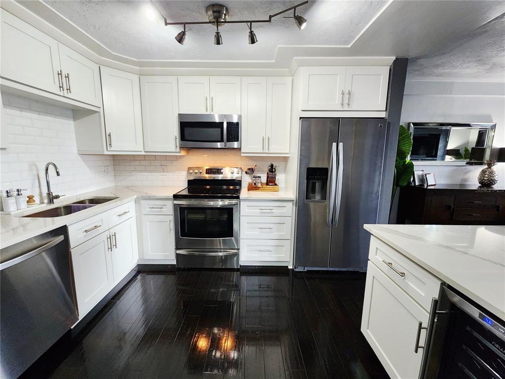 A kitchen features white cabinets, stainless steel appliances, a subway tile backsplash, and dark flooring — 4651 1ST STREET NE UNIT 306, ST PETERSBURG, FL