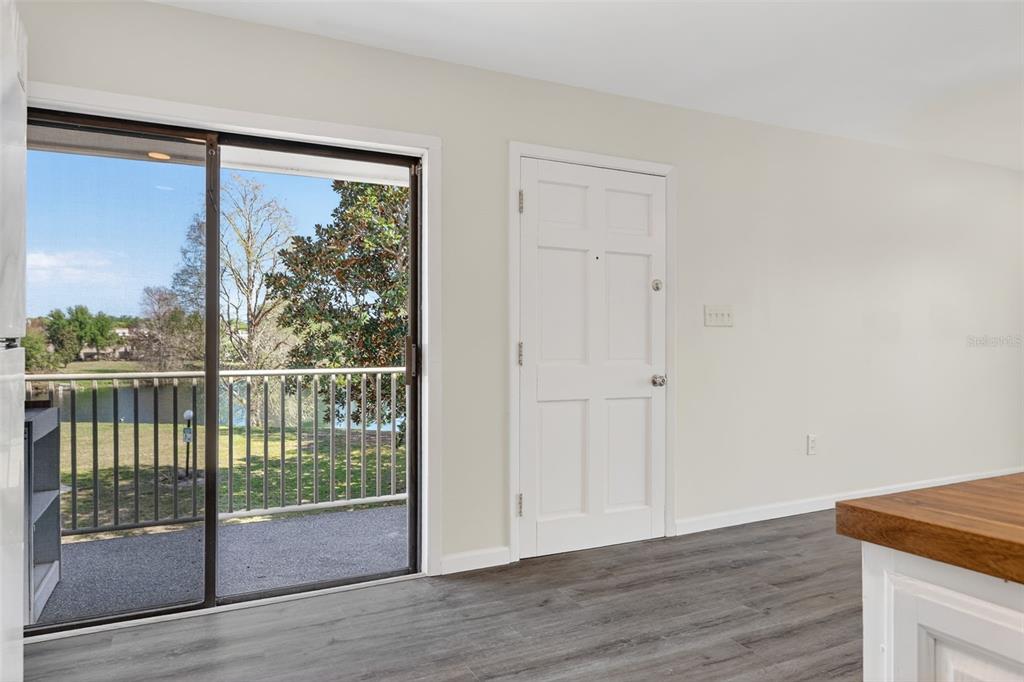 A room with wood-look flooring, a white door, and a sliding glass door overlooking a lake — 1935 CONWAY ROAD UNIT F6, ORLANDO, FL
