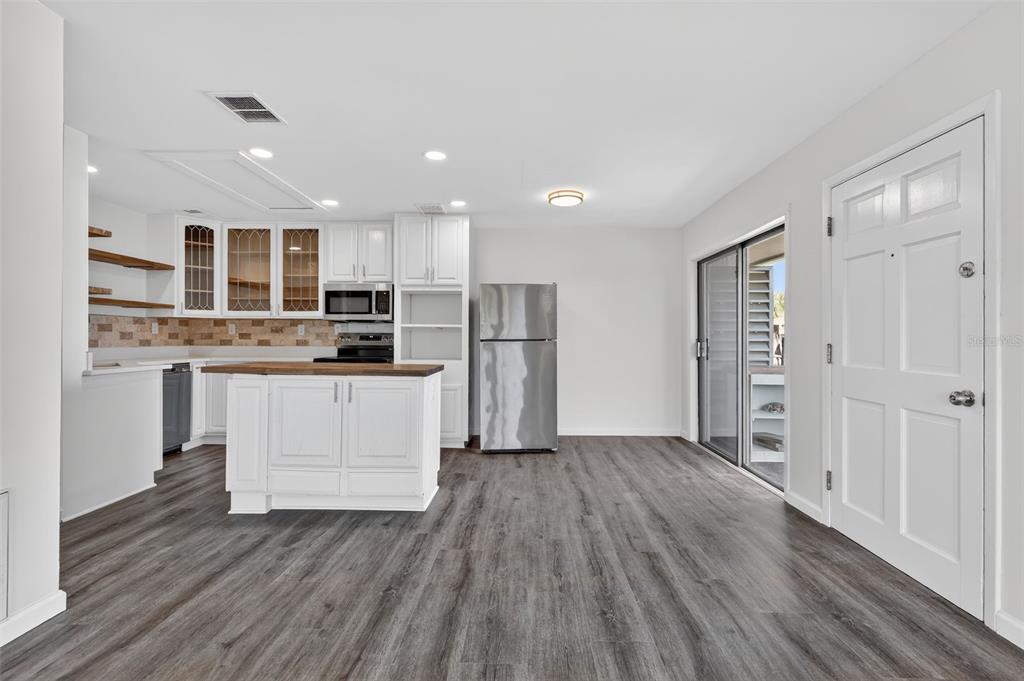 A kitchen with white cabinets, a wood-topped island, and stainless steel appliances opens to a patio — 1935 CONWAY ROAD UNIT F6, ORLANDO, FL
