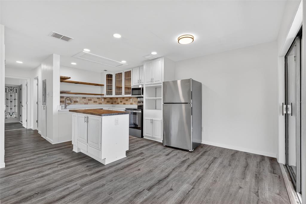 A kitchen features white cabinets, a wooden island, stainless steel appliances, and gray wood flooring — 1935 CONWAY ROAD UNIT F6, ORLANDO, FL