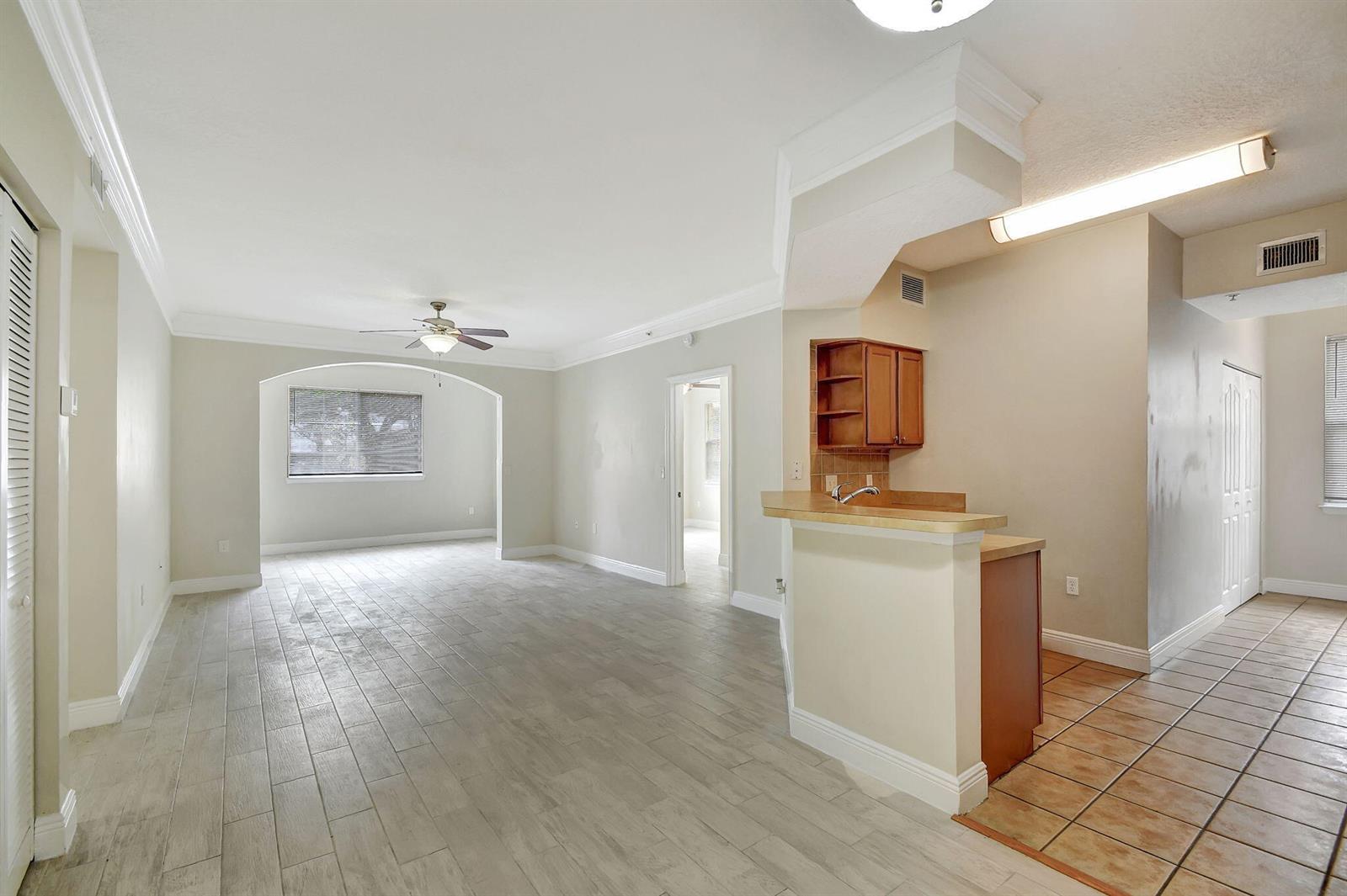 An open-concept living area features light wood-look tile flooring, a kitchen peninsula, and arched transitions — 9849 Baywinds Drive # 8101, West Palm Beach FL 33411, WEST PALM BEACH, FL