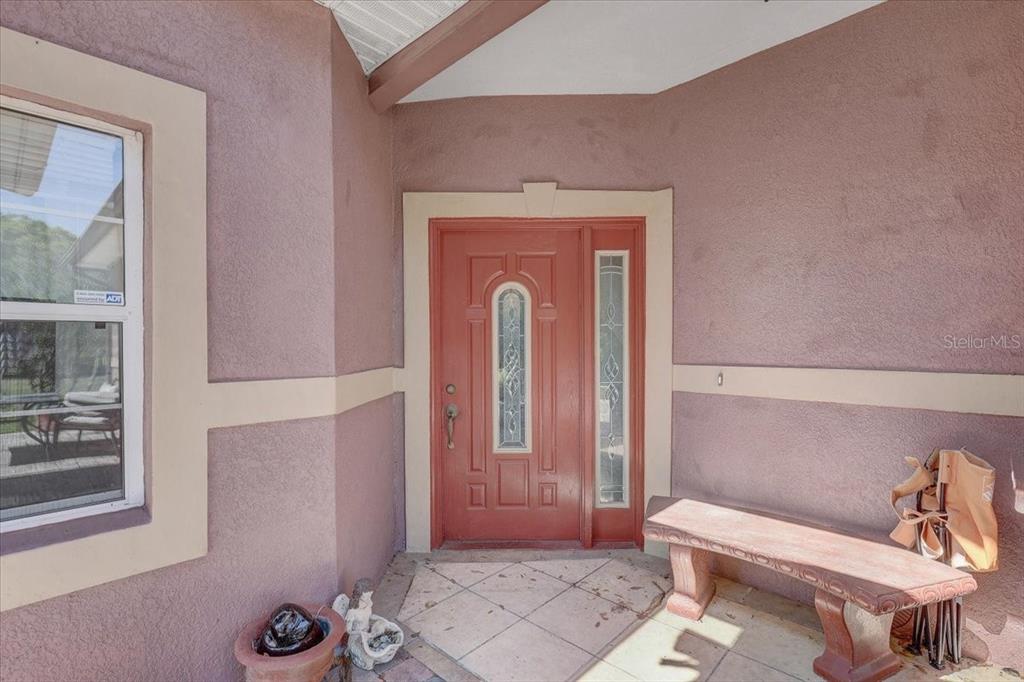 A red front door with a glass insert is set within a stucco entryway — 4954 EWELL ROAD, LAKELAND, FL
