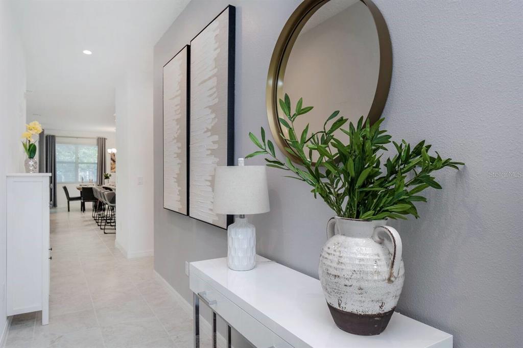 A white console table with a lamp and vase sits in a gray-walled hallway — 8937 AMELIA DOWNS TRAIL, KISSIMMEE, FL