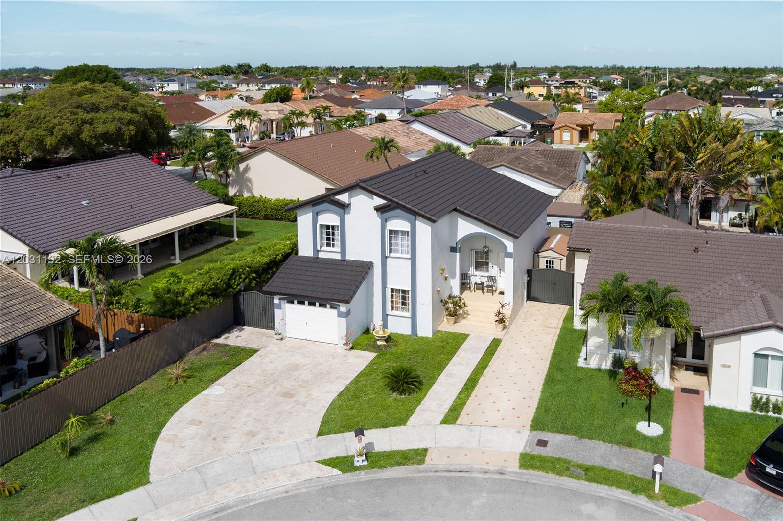 An aerial view shows a two-story white house with a dark roof and paved driveway — 1084 SW 142nd Pl, Miami FL 33184, MIAMI, FL