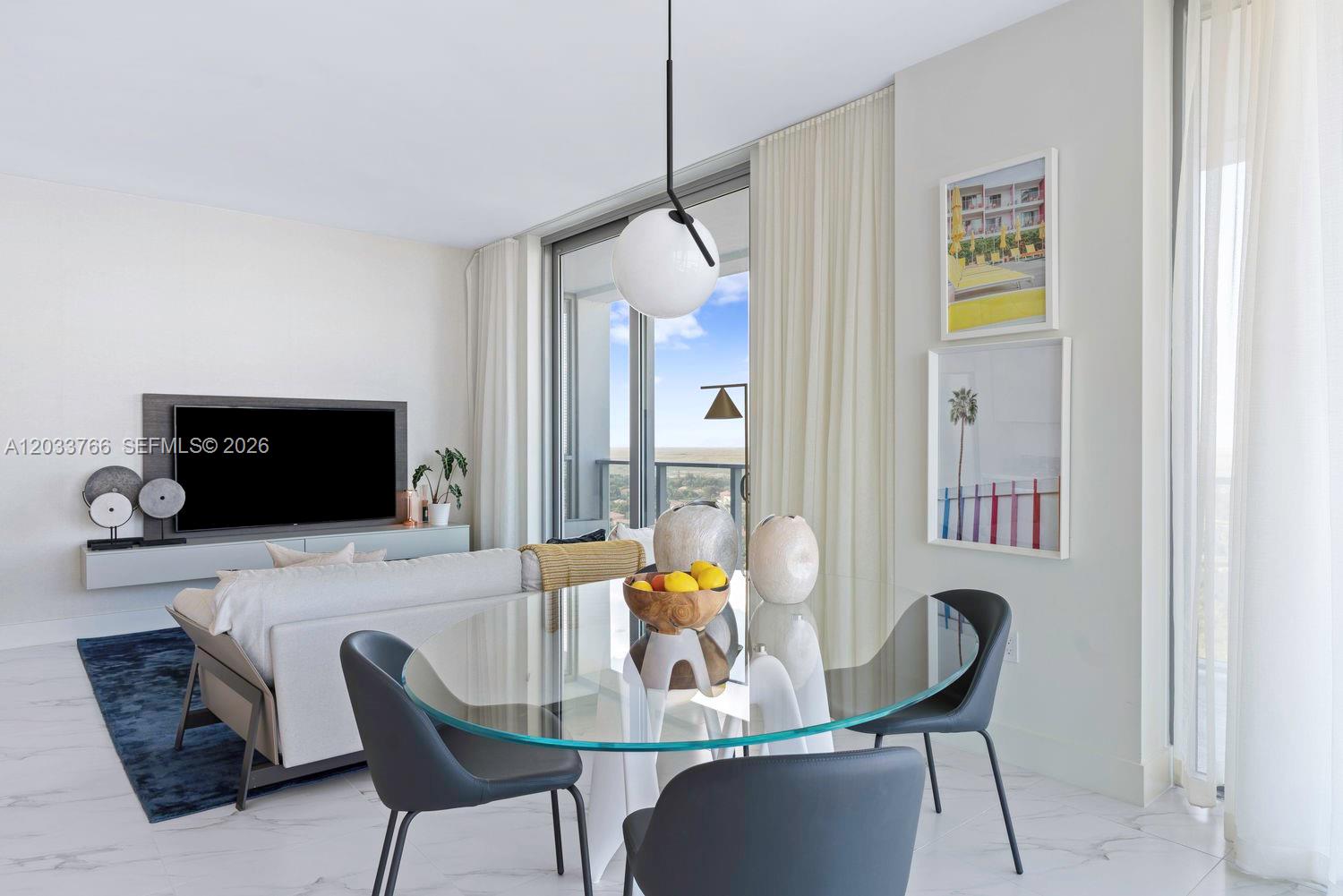 A modern living and dining area features a glass table, gray chairs, and balcony views — 2000 Metropica Way # 1810, Sunrise FL 33323, SUNRISE, FL