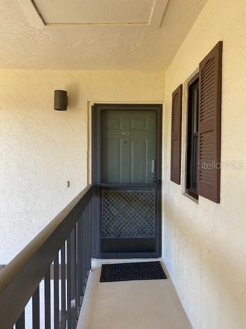 An exterior view of a residential apartment entrance with a screen door and brown shutters — 19505 QUESADA AVENUE UNIT I202, PORT CHARLOTTE, FL